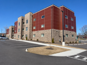Three-story SIP apartment building with brick base and red panel exterior at Prices Fork Village Apartments in Blacksburg, VA