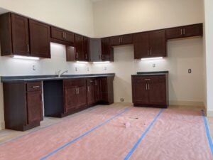 Newly installed kitchen with dark wood cabinets and dark countertops in a Prices Fork Village Apartments unit, floor still protected during construction
